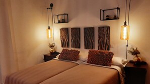 Ein Doppelbett mit zwei Kissen, ein Nachttisch mit Lampe und Wandbild.