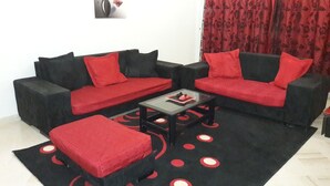 A living room with a black sofa set, red cushions, and a black coffee table. - Spacious Modern app Richly Furnished (Tunis)