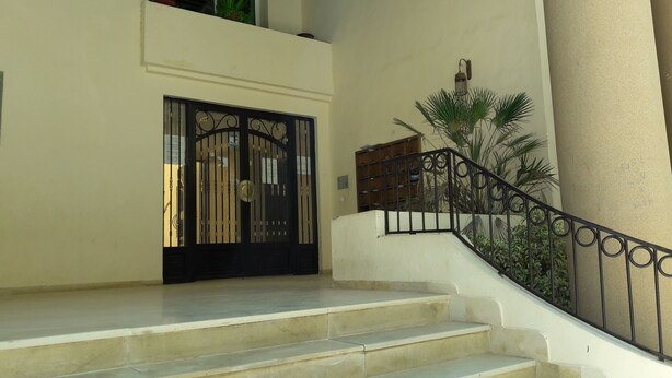 A staircase with a black metal railing leading to a door with a decorative metal gate. - Spacious Modern app Richly Furnished (Tunis)