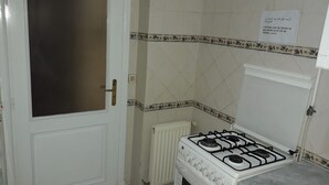 A kitchen with a white gas stove, a white door with a frosted glass panel, and a radiator. - Spacious Modern app Richly Furnished (Tunis)