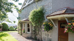 A stone building with a wooden door and windows, a gravel path, and a well-maintained lawn. - The Redgarth (Inverurie)