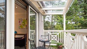 A balcony with a glass door leading to a room, a small table with chairs, and a potted plant. - The Redgarth (Inverurie)