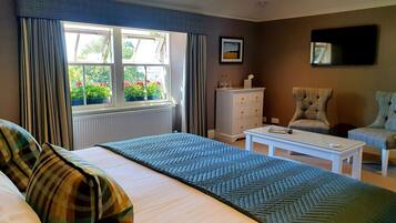 Un dormitorio con cama, cómoda, silla, mesa y ventana con cortinas.