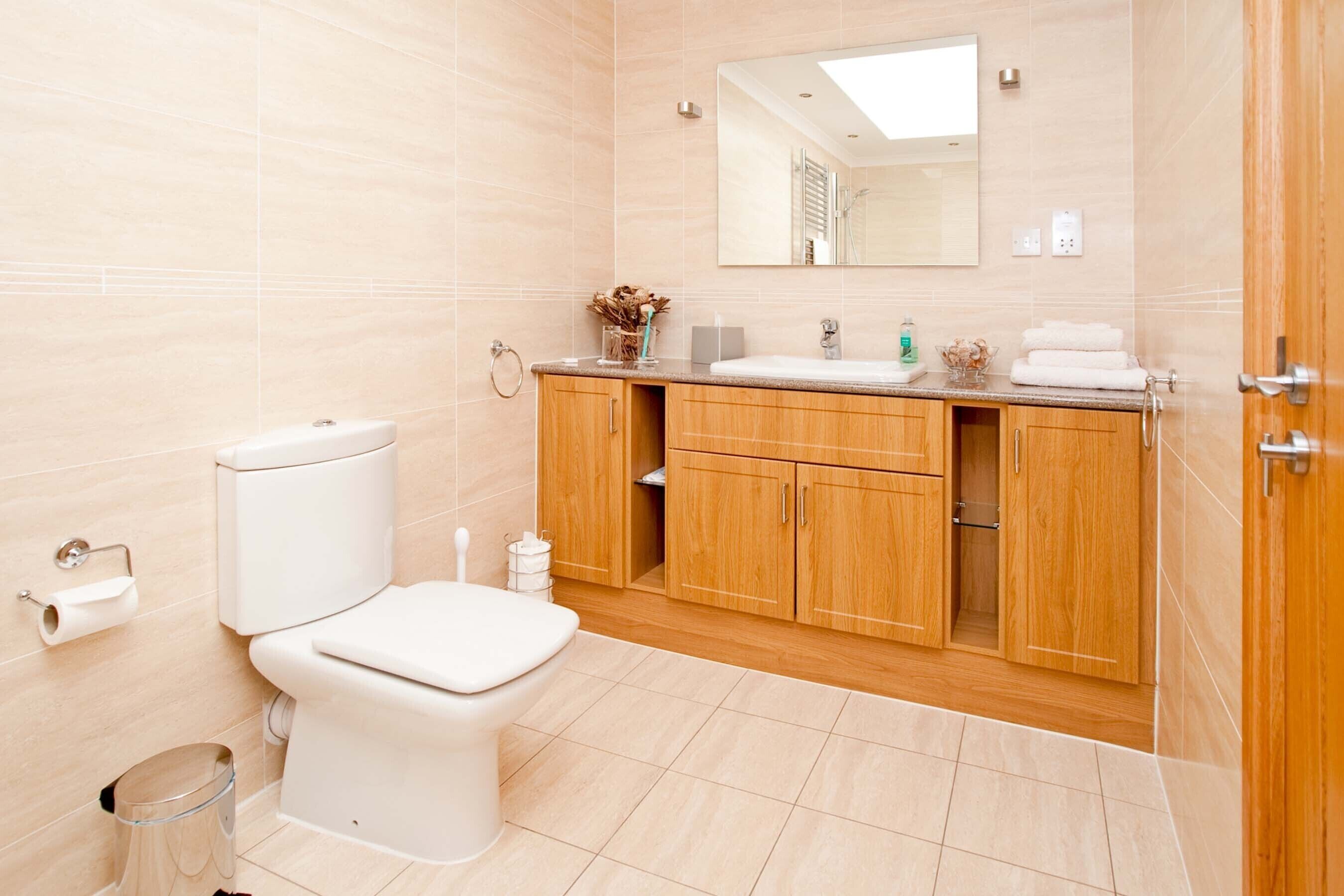 A modern bathroom with a toilet, sink, and wooden cabinets.