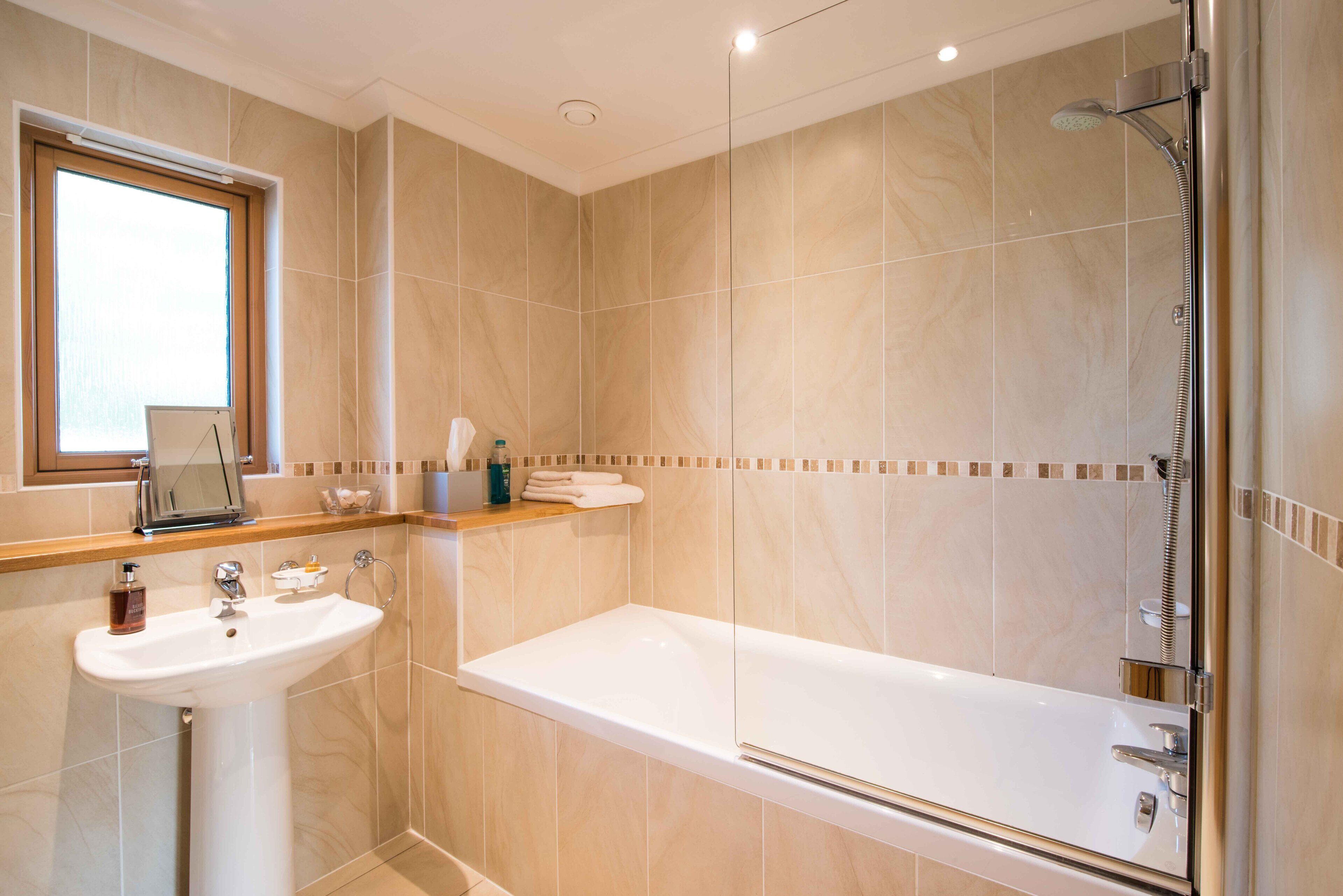 Un baño moderno con lavamanos, espejo y ducha.