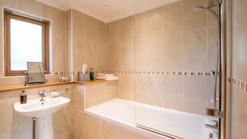 Un baño moderno con lavamanos, espejo y ducha.