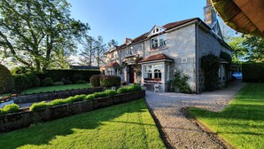A stone house with a well-maintained lawn and a gravel driveway leading to the entrance. - The Redgarth (Inverurie)