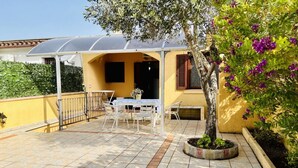 A patio with a table and chairs, a covered seating area, and a potted tree. - Appartamenti San Teodoro IV con BBQ, A/C e WIFI (San Teodoro)