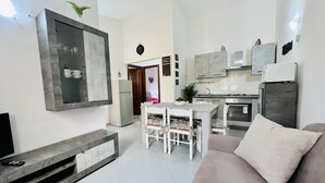 A modern kitchen with white cabinets, a dining table with chairs, and a built-in oven. - Appartamenti San Teodoro IV con BBQ, A/C e WIFI (San Teodoro)