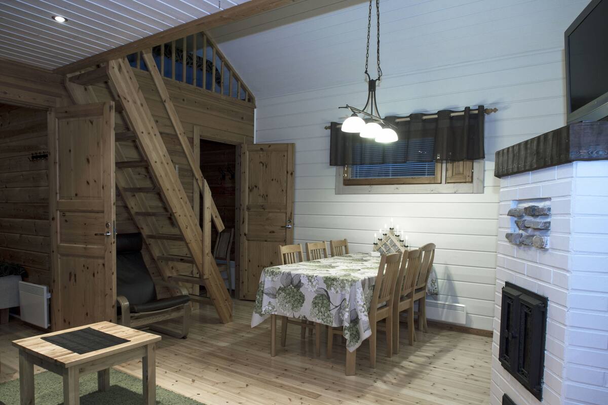 Ein rustikales Blockhaus mit Essbereich, Treppe und Kamin.