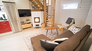 Un salon moderne avec un canapé, un téléviseur, une cheminée et un escalier en bois.