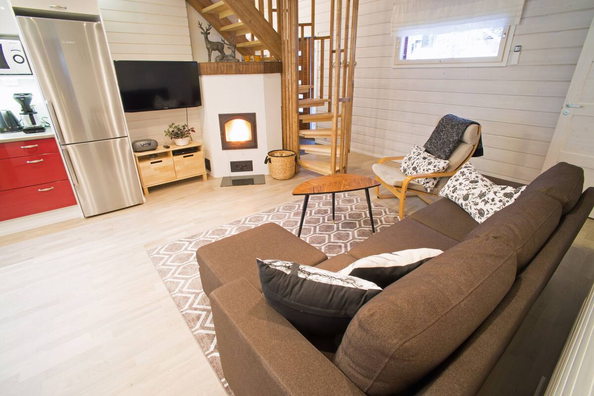 Ein modernes Wohnzimmer mit einer Couch, einem Fernseher, einem Kamin und einer Holztreppe.