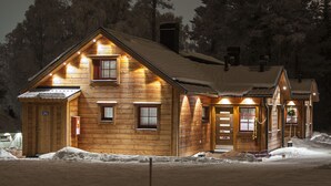 Une cabane en bois avec un toit en pente, de nombreuses fenêtres et un sol recouvert de neige.