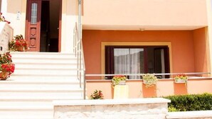 A multi-story building with a balcony on the second floor, a door with a window on the first floor, and potted plants on the ground floor. - Apartments "Labinac" Pula- Apartment I (Pula)