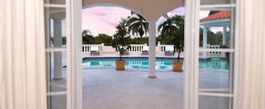 A pool area with a view of a sunset, palm trees, and a gazebo.