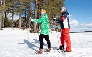 Two people cross-country skiing on a snowy landscape with trees and a clear sky. - Lentiira Holiday Village (Kuhmo)