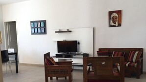 A living room with a sofa set, a television, and a painting on the wall. - Independent Villa With Private Pool, Covered Parking (Mezraia)