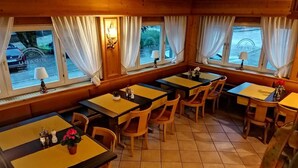 A restaurant with multiple tables and chairs, large windows with curtains, and a view of the street outside. - PiPaBu Restaurant & Hotel (Rheinfelden (Baden))