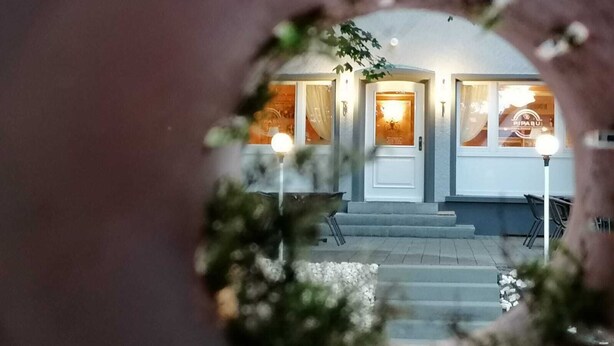 A hotel entrance with a white door, steps leading up to it, and a sign above the door. - PiPaBu Restaurant & Hotel (Rheinfelden (Baden))