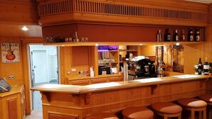 A wooden bar area with stools, a coffee machine, and shelves with bottles. - PiPaBu Restaurant & Hotel (Rheinfelden (Baden))