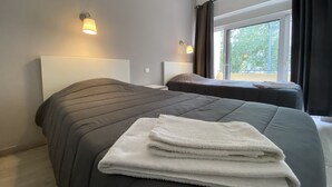 A hotel room with two beds, a large window, and a view of the outdoors. - Hostel Paris (Marinha Grande)