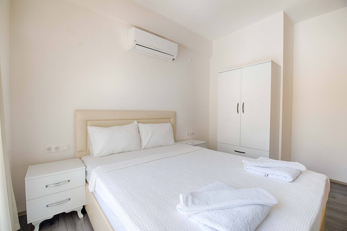 A bedroom with a bed, nightstand, and wardrobe.