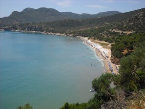 A coastal landscape with a beach, clear water, and a mountainous backdrop. - Meltemia Studio Samos N3 Glicorissa (Samos)