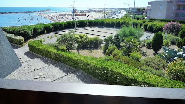 Un resort costero con playa, jardines ajardinados y vistas al mar.