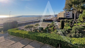 Un área residencial costera con un sendero pavimentado, jardines cuidados y un edificio con balcones con vista a la playa.