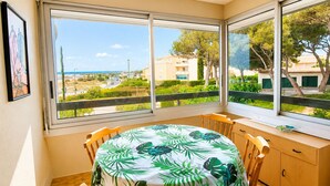 Una habitación con una mesa de comedor, sillas, vista al mar y un balcón.