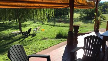 A patio area with outdoor seating, a pergola, and a view of a grassy landscape.
