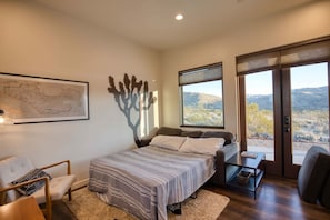 A bedroom with a bed, a chair, a coffee table, a map on the wall, and a view of the outdoors.