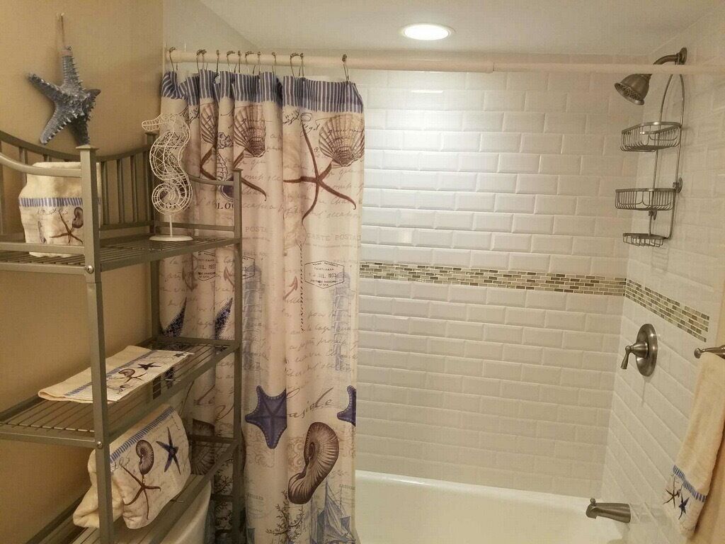 Un baño con ducha, toallero y repisas con toallas.