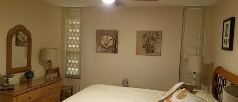 Un dormitorio con cama, cómoda, ventilador de techo y obras de arte en las paredes.