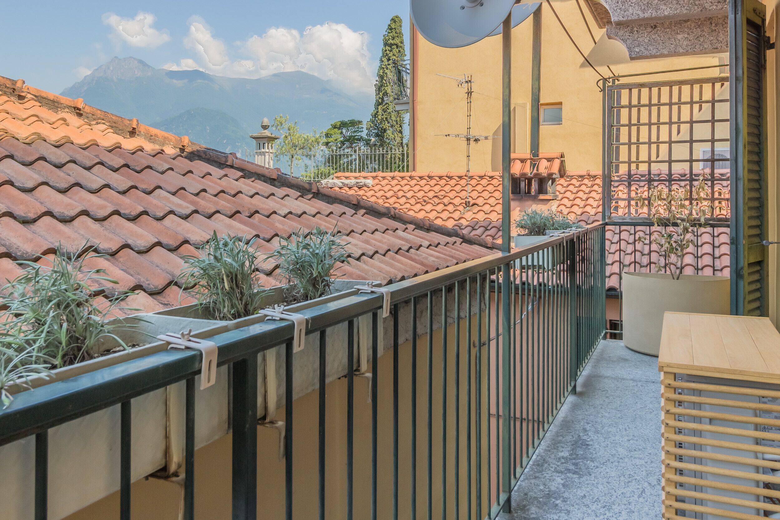 A balcony with a tiled roof, a satellite dish, and a view of mountains.