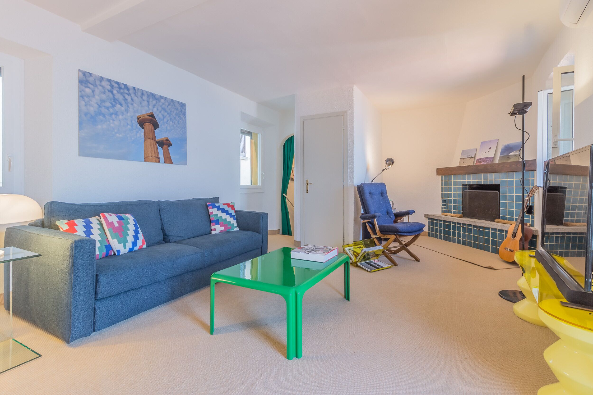 A living room with a blue sofa, a green coffee table, and a blue armchair.