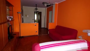A room with orange walls, a red sofa, a bed with a striped blanket, a floor lamp, and a mirror. - inn Stellone of Marco Pastore (Villastellone)
