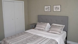 A bedroom with a bed, a nightstand, a wardrobe, and two framed pictures on the wall. - Discover "a Perfect Place" in Grand Forks (Grand Forks)