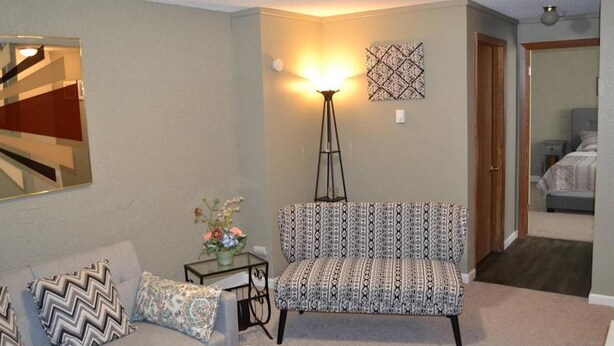 A living room with a sofa, a floor lamp, a patterned chair, a small table with a vase, and a mirror on the wall. - Discover "a Perfect Place" in Grand Forks (Grand Forks)