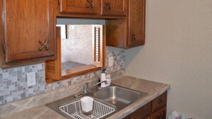 A kitchen with wooden cabinets, a stainless steel sink, and a tiled backsplash. - Discover "a Perfect Place" in Grand Forks (Grand Forks)