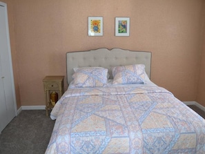 Une chambre à coucher avec un lit, une table de chevet et deux tableaux encadrés accrochés au mur.