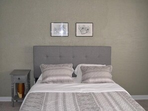A neatly made bed with a grey headboard, two pillows, and a grey nightstand with a drawer. - Discover "a Perfect Place" in Grand Forks (Grand Forks)