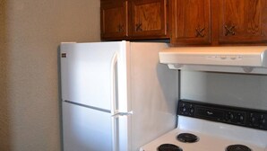 A kitchen with wooden cabinets, a white refrigerator, and a stove with black controls. - Discover "a Perfect Place" in Grand Forks (Grand Forks)