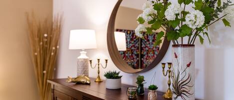 A wooden dresser with a mirror, a vase with white flowers, and various decorative items.