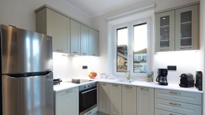 Una cocina moderna con electrodomésticos de acero inoxidable, armarios de tonos claros y un ventanal con vistas al exterior.