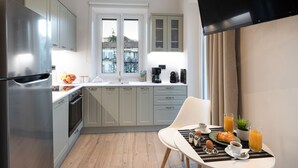 Una cocina moderna con un refrigerador de acero inoxidable, un comedor con una mesa dispuesta para el desayuno, y una vista por la ventana.