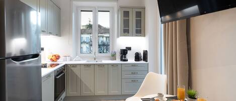 A modern kitchen with a stainless steel refrigerator, a dining area with a table set for breakfast, and a view through the window.