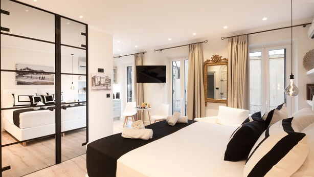 Una habitación de hotel moderna con una cama grande, televisión, escritorio y vistas a la ciudad.