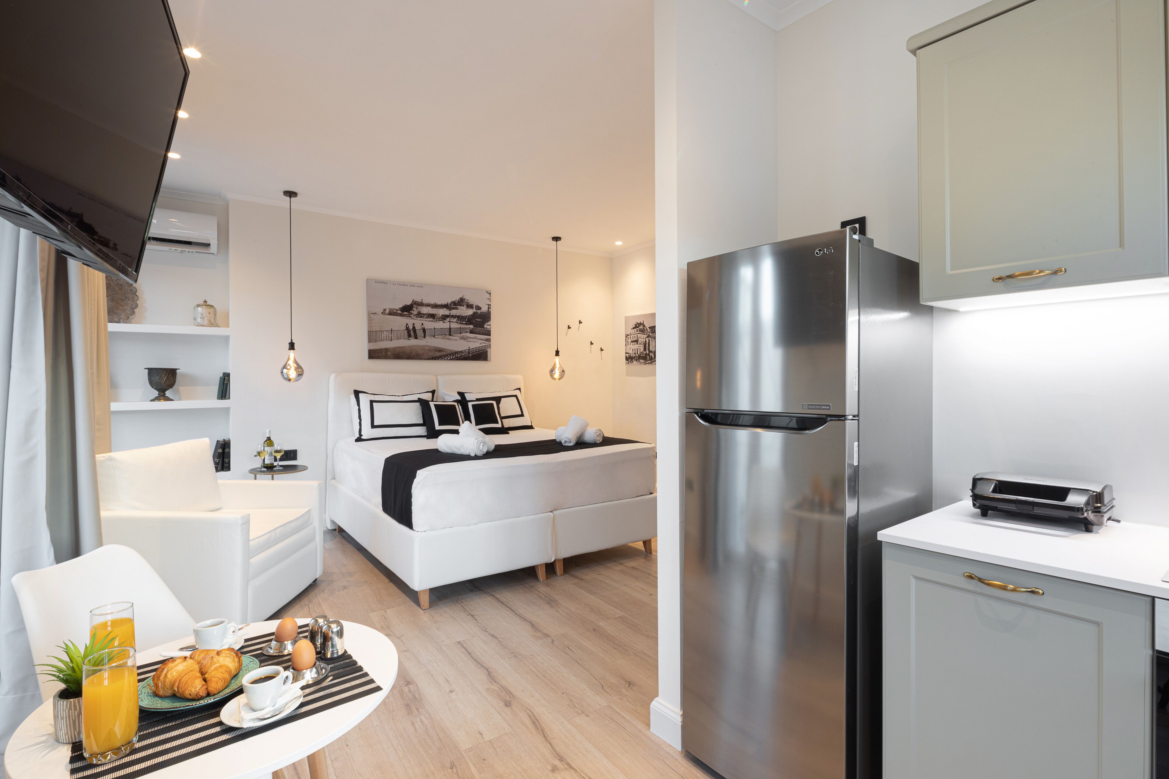 A modern hotel room with a kitchenette, a dining area, and a bed.