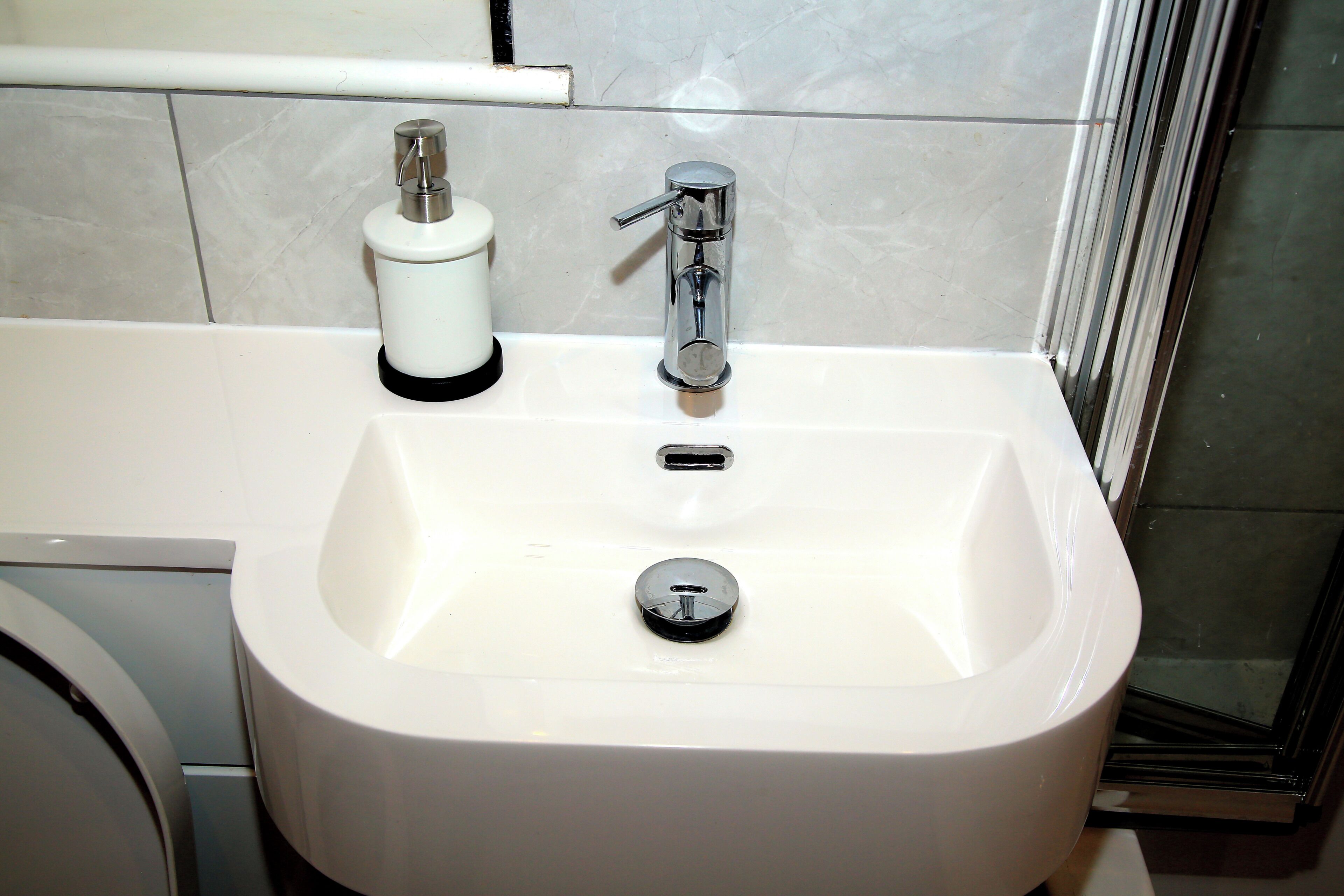 Une salle de bain avec un lavabo blanc, un robinet et un distributeur de savon.